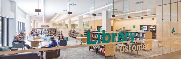 Looking into the library through the front window, seeing people sitting reading 