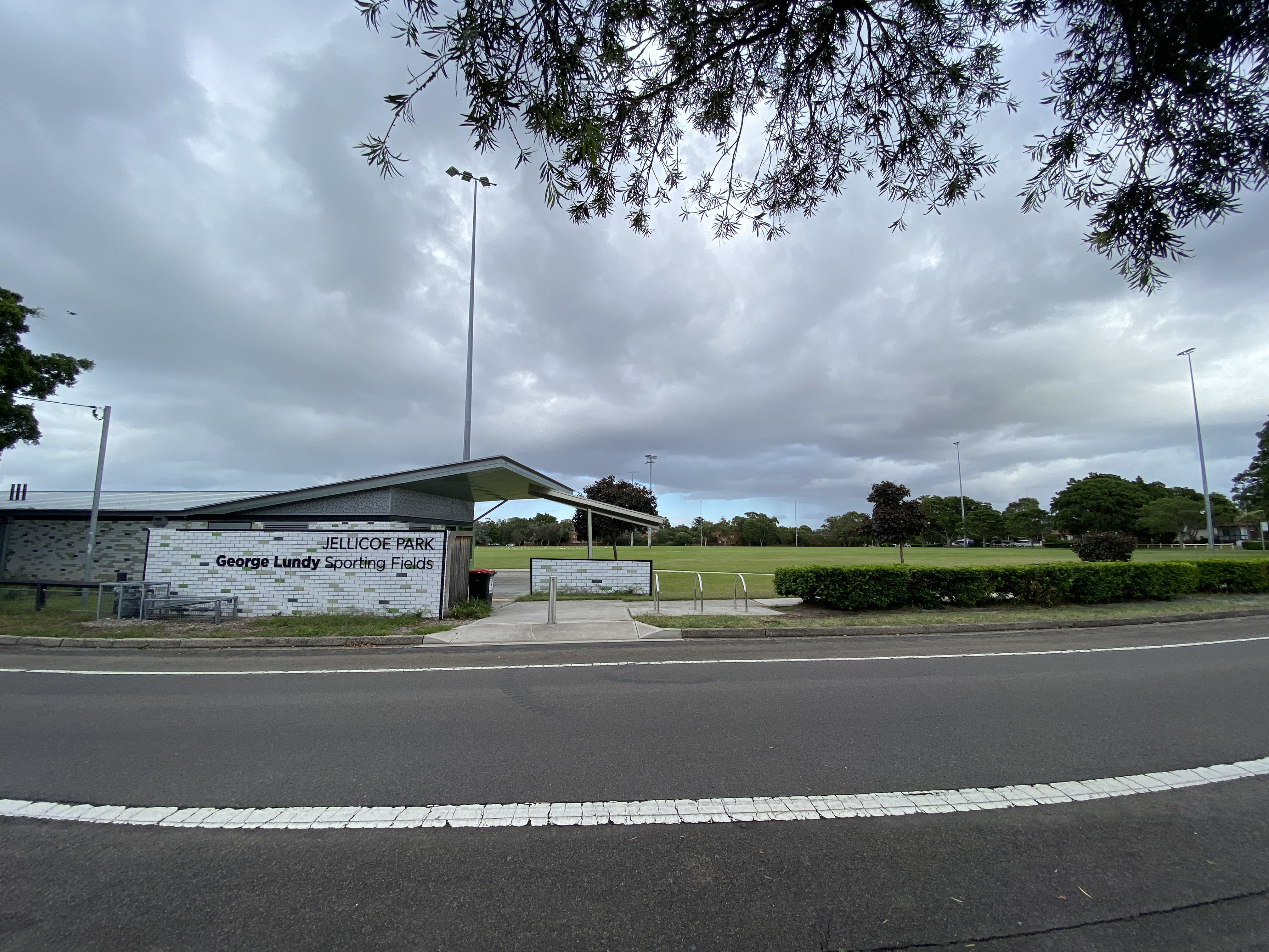 Jellicoe park field and building viewed from the opposite side of a road on an overcast day