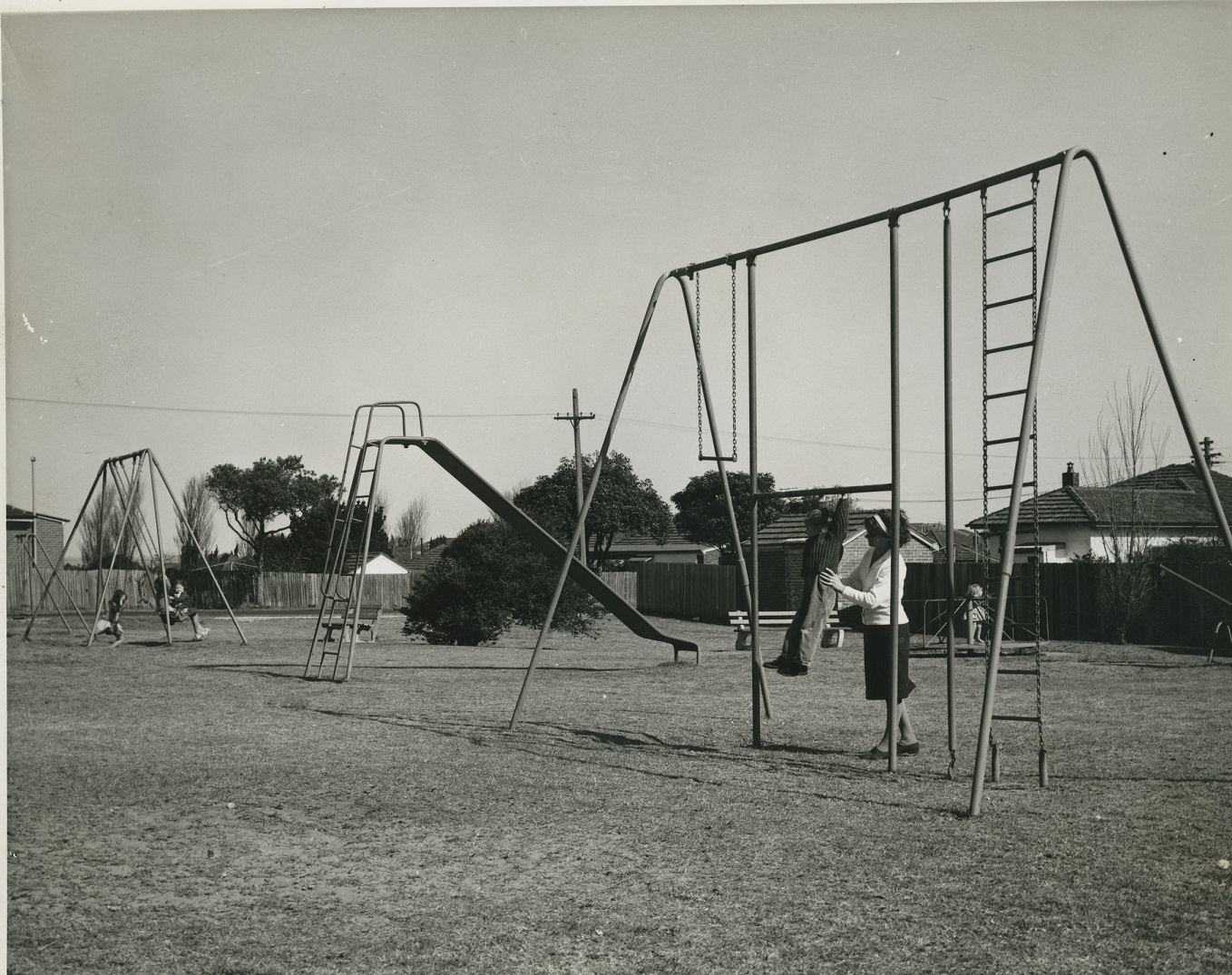 historical photo of children playing on park swings