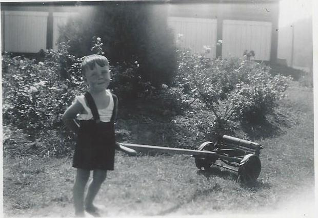 historical photo of young boy mowing a lawn