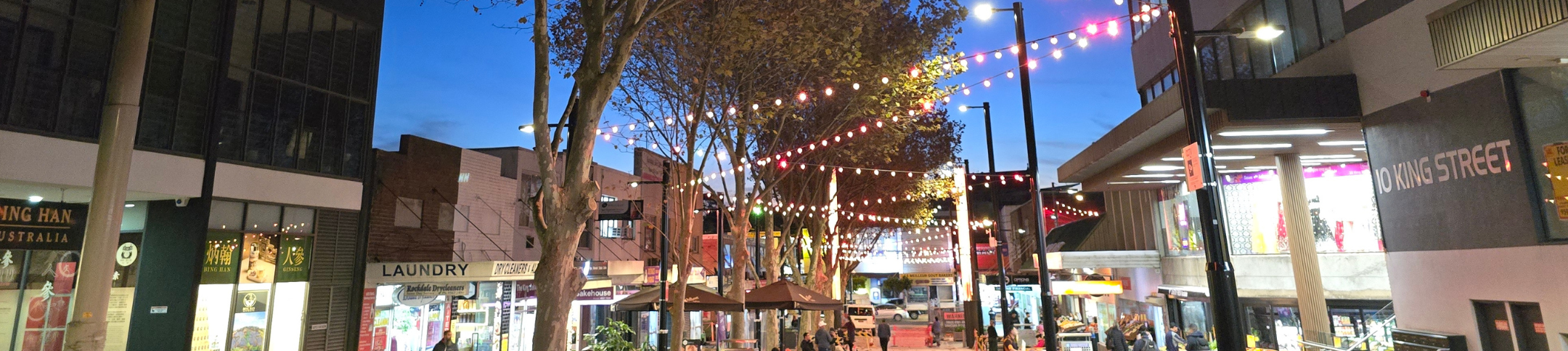 Lit up street with shops in Rockdale at night