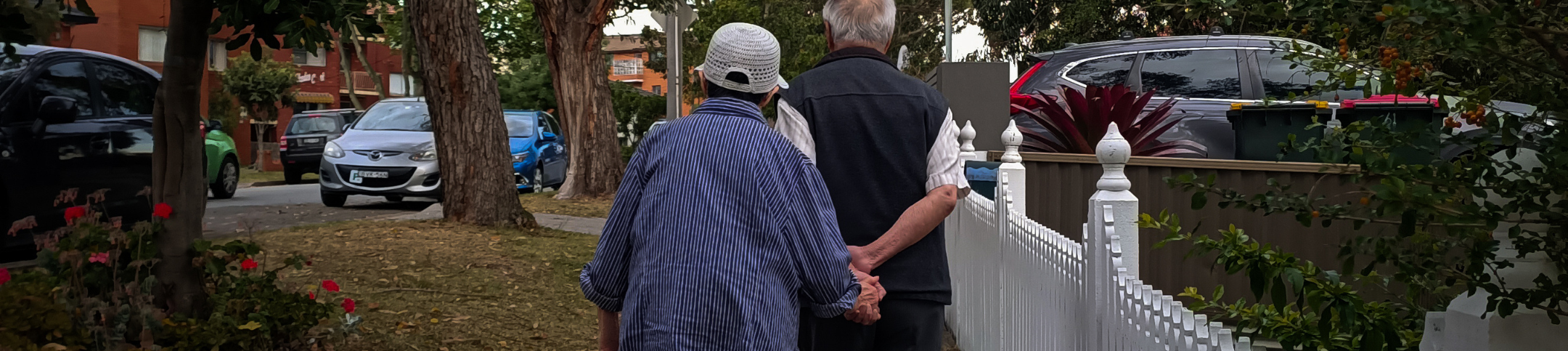 Two people holding hands walking on the sidewalk